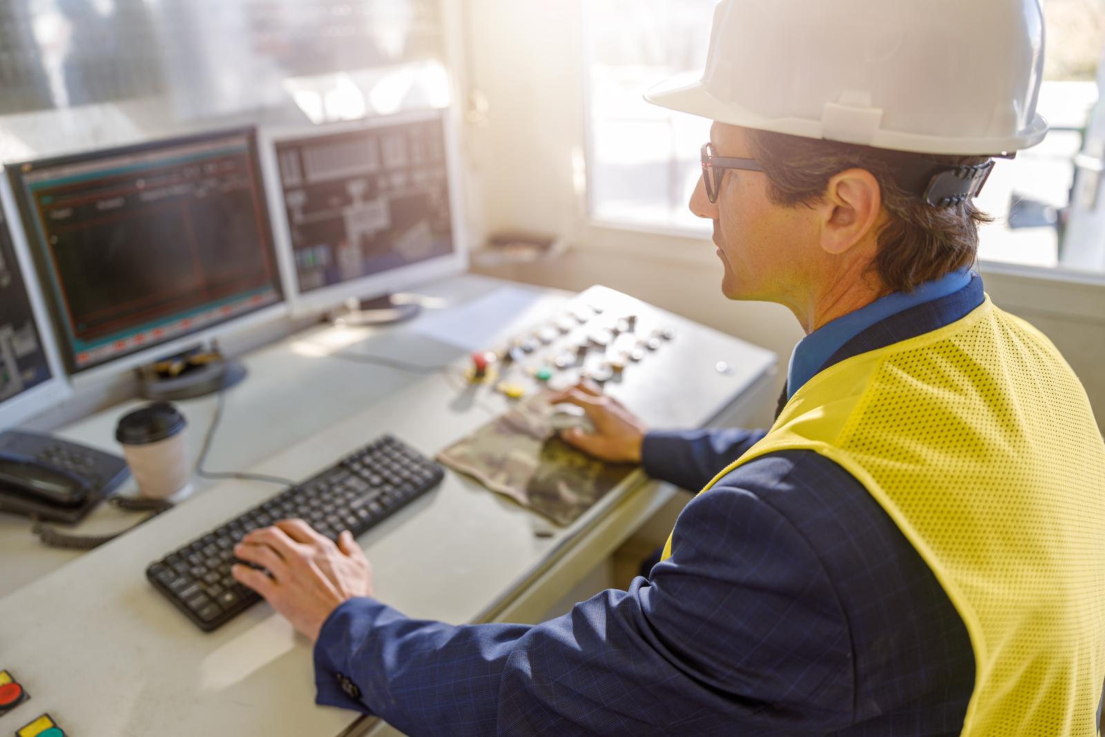 Male worker using computers at manufacturing plant